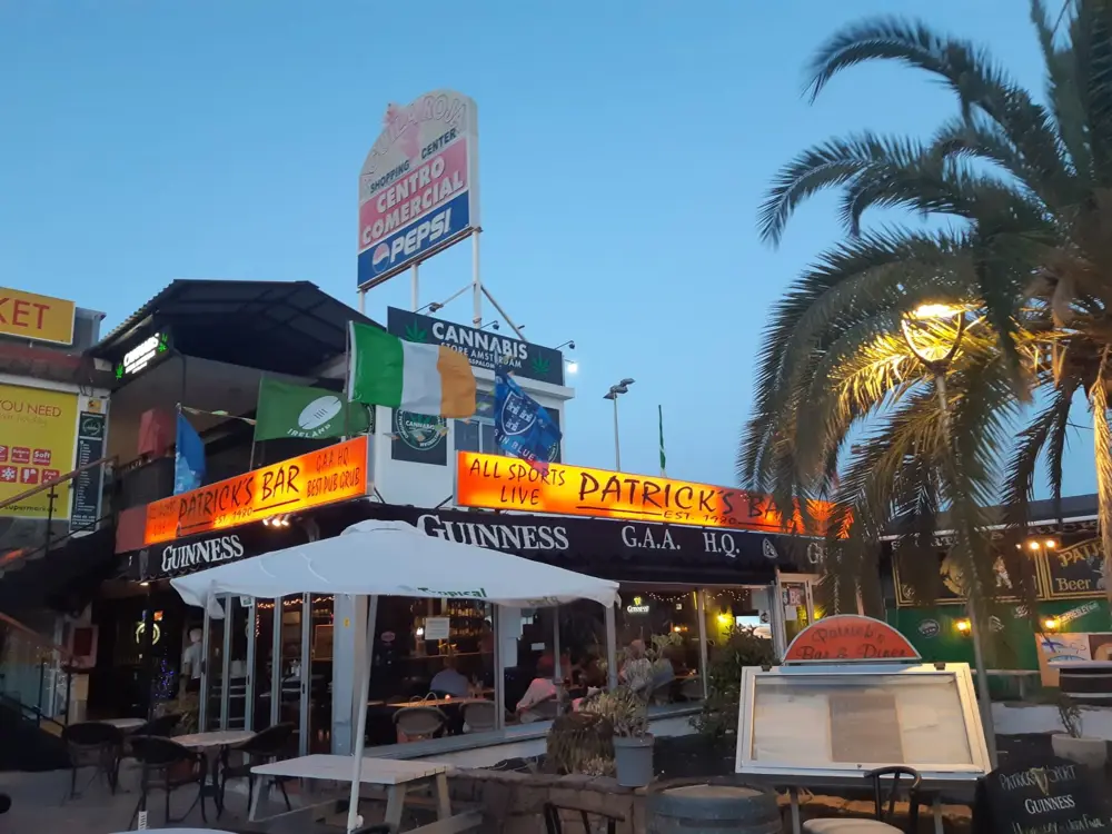 Irish Pub im Águila Roja bei Sonnenuntergang, mit dem Schild des Einkaufszentrums