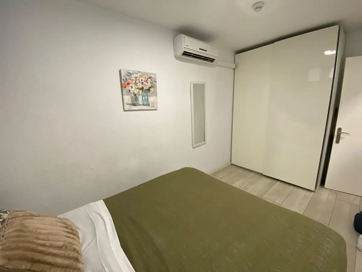Schlafzimmer mit Doppelbett, Klimaanlage und weißem Schiebetürenschrank