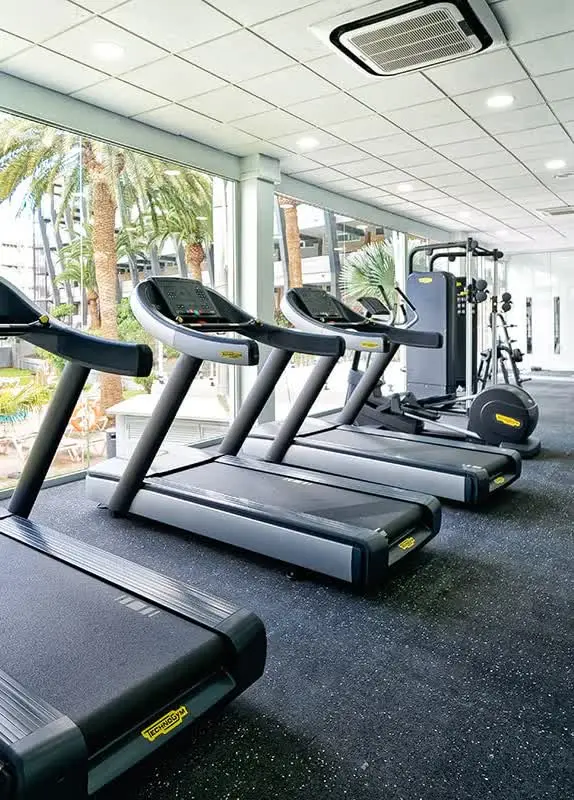 Fitnessraum mit Laufbändern und Blick in den Garten