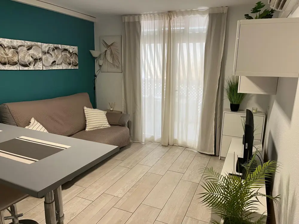 Wohnzimmer mit petrolfarbener Wand, Schlafsofa und Balkontür