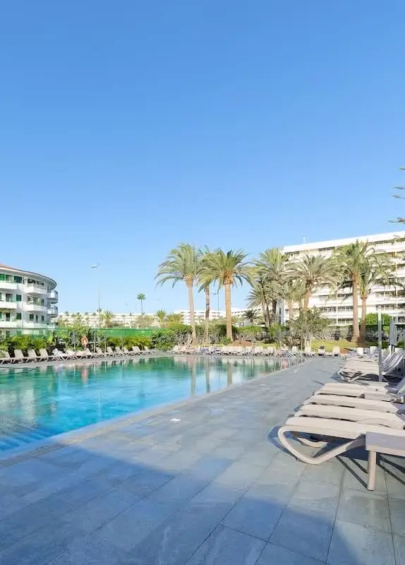 Langer Pool mit Liegen und Palmen